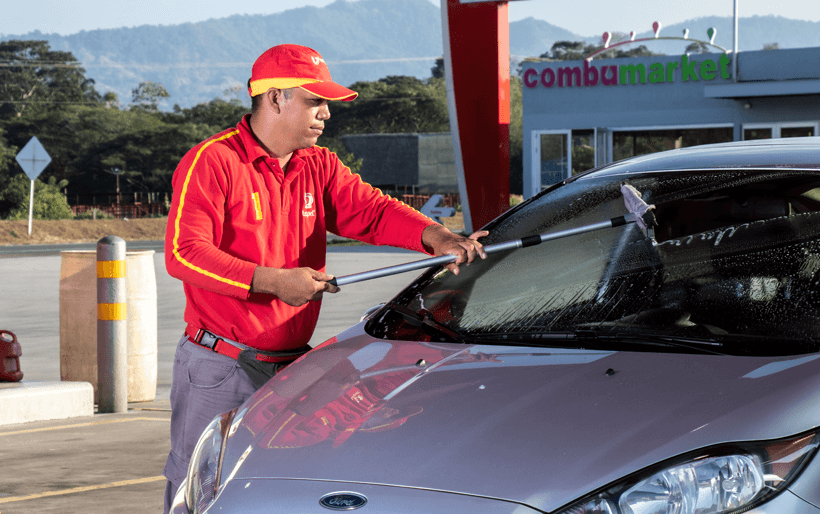 Vendedor de combustible limpiando vidrio de vehiculo